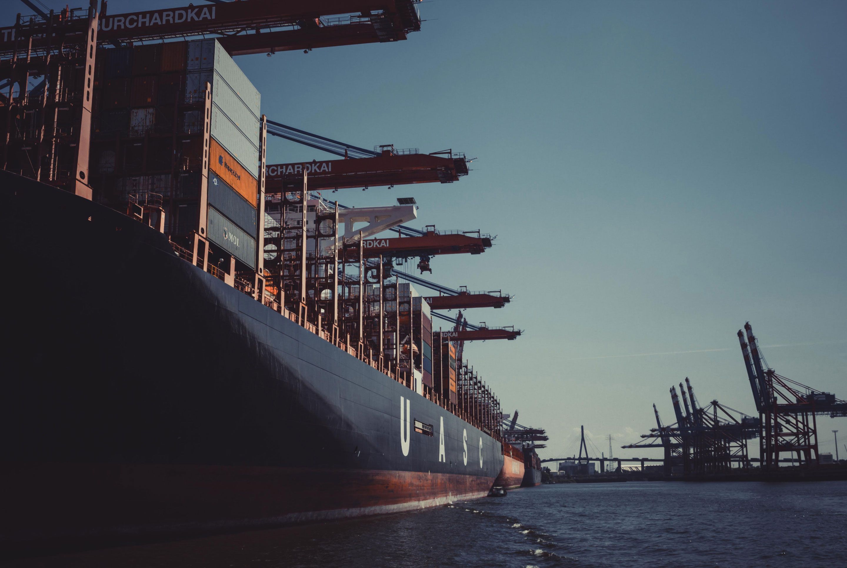 Large cargo ship being unloaded at a port. 