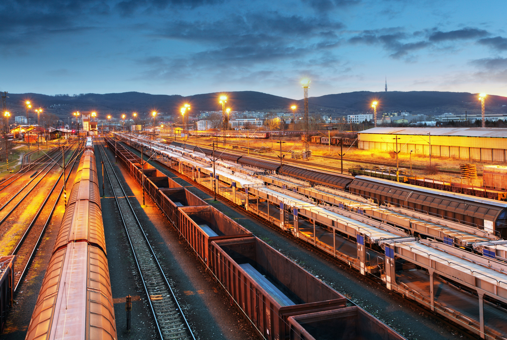 Rail freight yard at night with cargo being loaded and shipped. 